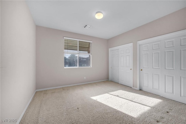 unfurnished bedroom featuring multiple closets and carpet