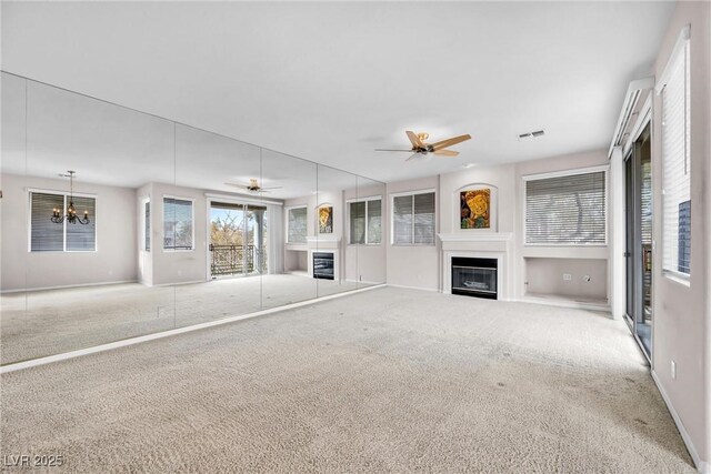 unfurnished living room featuring ceiling fan with notable chandelier and carpet