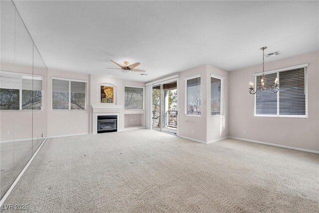 unfurnished living room featuring ceiling fan with notable chandelier and carpet