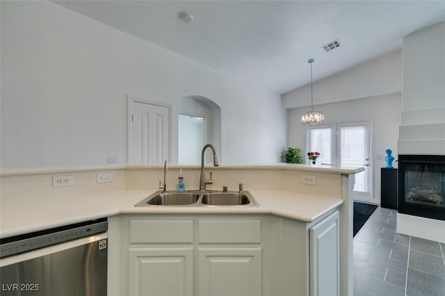 kitchen featuring white cabinets, dishwasher, a multi sided fireplace, sink, and lofted ceiling