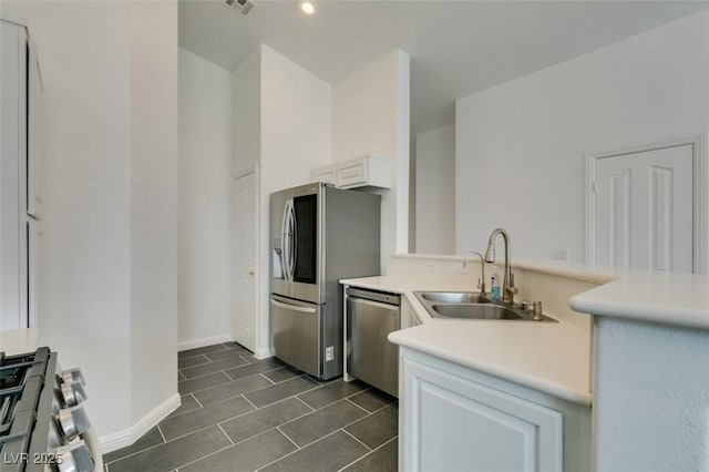 kitchen with stainless steel appliances, white cabinets, sink, and dark tile patterned flooring