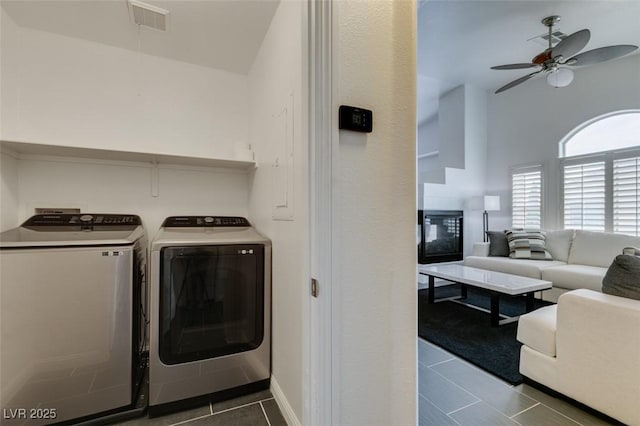 washroom with independent washer and dryer, dark tile patterned floors, and ceiling fan