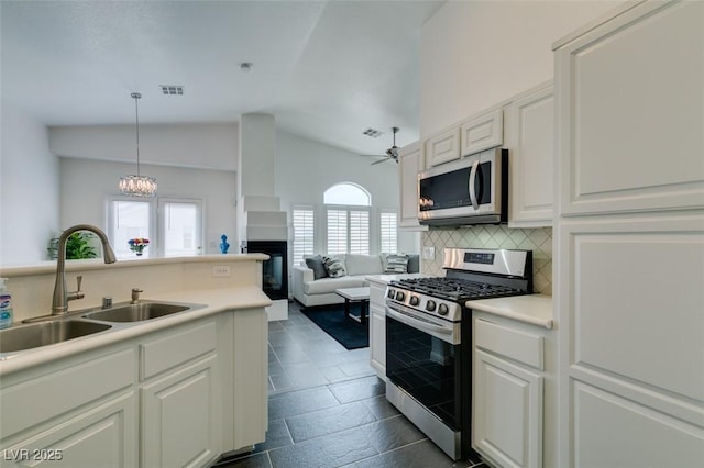 kitchen featuring appliances with stainless steel finishes, hanging light fixtures, decorative backsplash, sink, and lofted ceiling