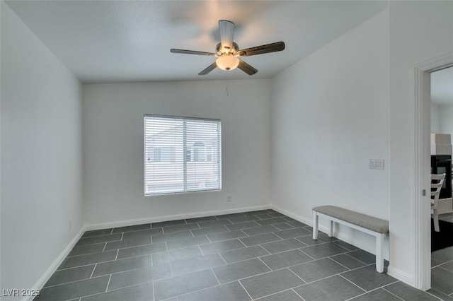 empty room with lofted ceiling, dark tile patterned flooring, and ceiling fan