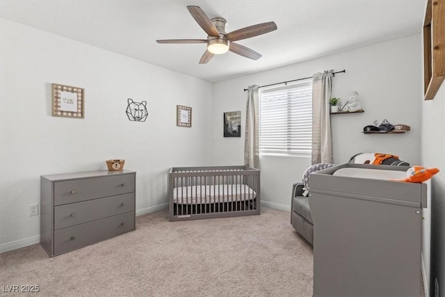 bedroom with a nursery area, ceiling fan, and light colored carpet