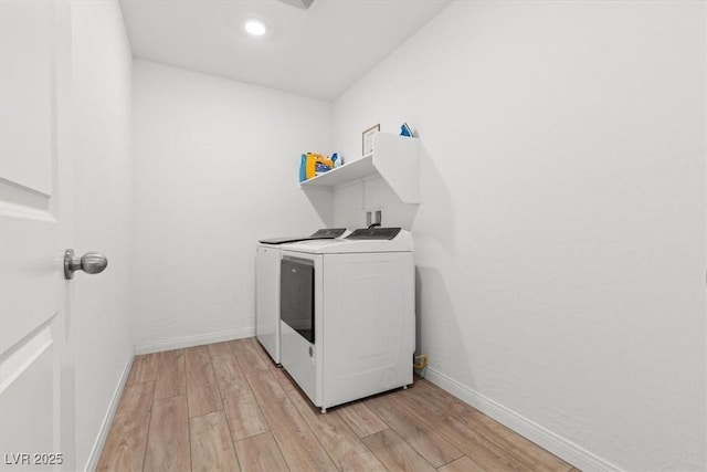 clothes washing area with washer and dryer and light hardwood / wood-style flooring