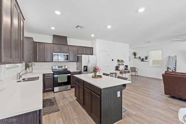 kitchen with sink, stainless steel appliances, light hardwood / wood-style floors, and a kitchen island