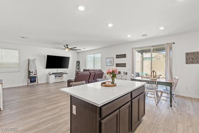 kitchen with a center island, ceiling fan, light hardwood / wood-style floors, and dark brown cabinets