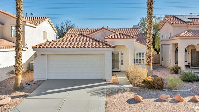 mediterranean / spanish-style home with a garage, concrete driveway, a tiled roof, and stucco siding