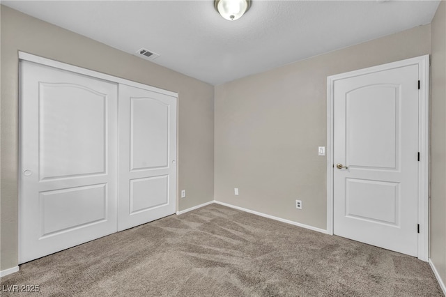 unfurnished bedroom with light colored carpet and a closet