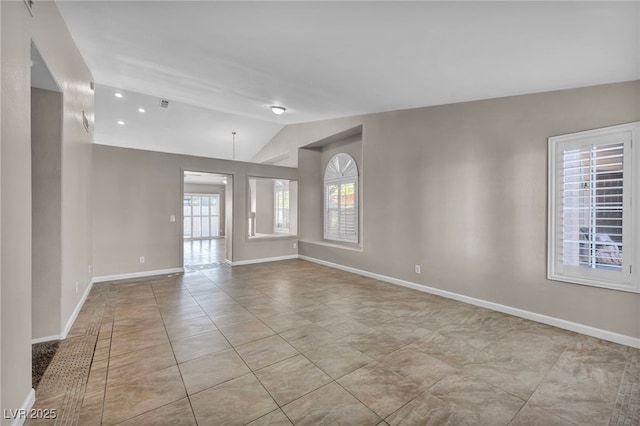 empty room with a healthy amount of sunlight, light tile patterned flooring, and lofted ceiling