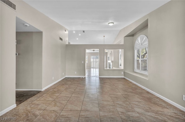 spare room featuring lofted ceiling, ceiling fan, light tile patterned floors, and a wealth of natural light