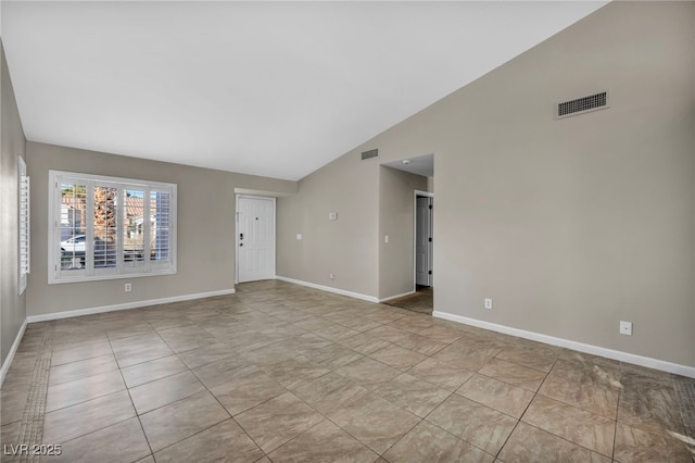 tiled spare room featuring lofted ceiling