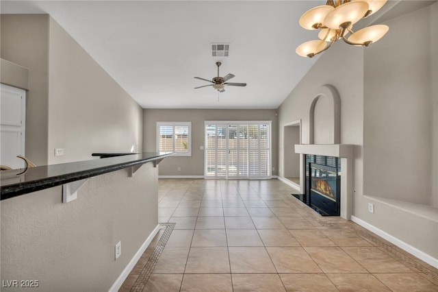 unfurnished living room featuring ceiling fan with notable chandelier, light tile patterned flooring, and lofted ceiling