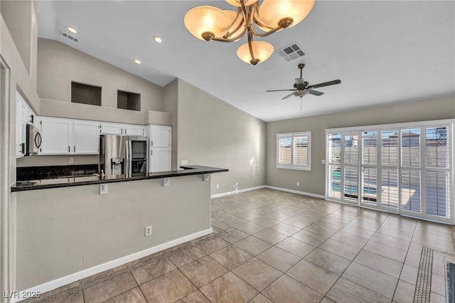 kitchen featuring stainless steel appliances, pendant lighting, white cabinetry, lofted ceiling, and ceiling fan with notable chandelier