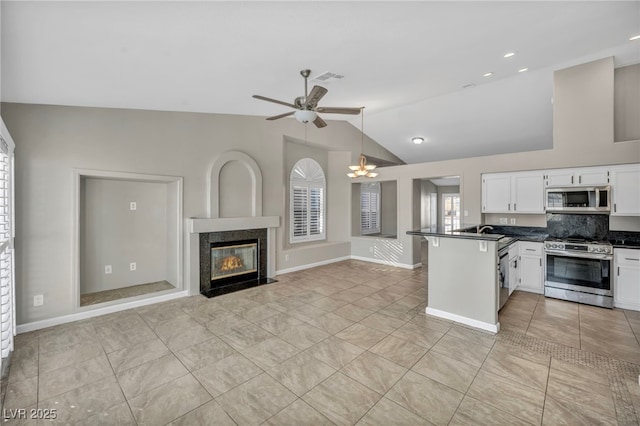 kitchen featuring vaulted ceiling, stainless steel appliances, kitchen peninsula, white cabinetry, and tasteful backsplash