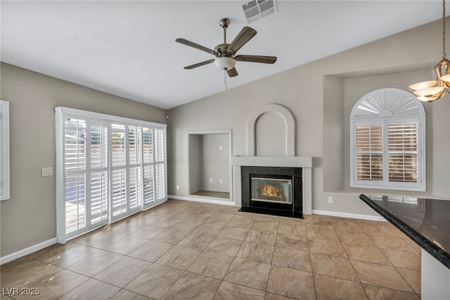 unfurnished living room with ceiling fan with notable chandelier, light tile patterned floors, and vaulted ceiling