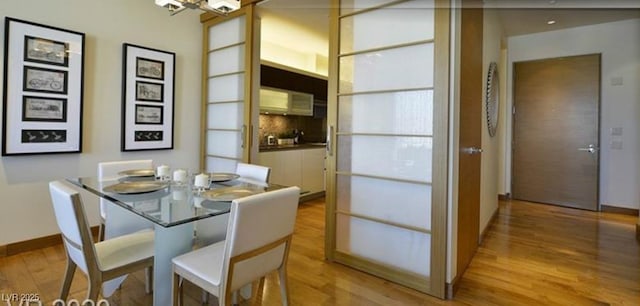 dining space with light wood-type flooring and a notable chandelier