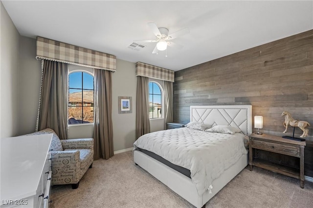 carpeted bedroom featuring ceiling fan and wood walls