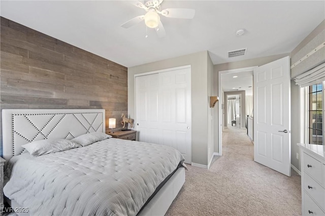 carpeted bedroom with ceiling fan, wooden walls, and a closet