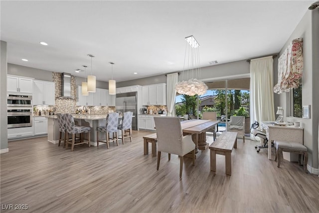 dining area with light wood-type flooring and a notable chandelier