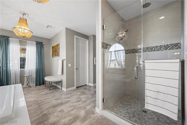 bathroom with a shower with door, an inviting chandelier, and a wealth of natural light