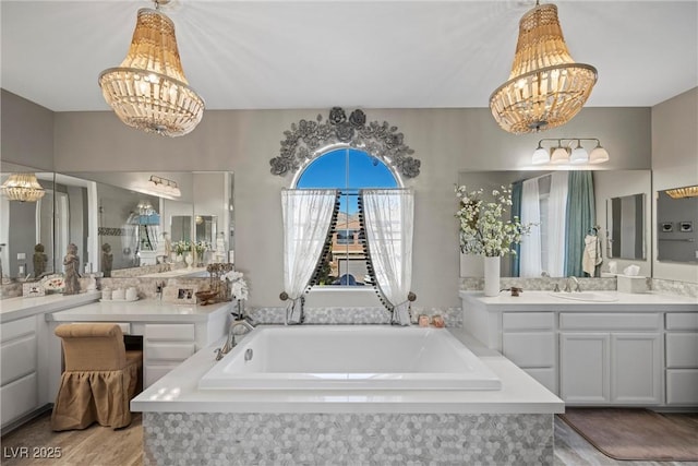 bathroom featuring a washtub, an inviting chandelier, and vanity