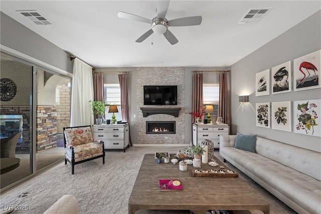 living room featuring ceiling fan, light colored carpet, and a fireplace