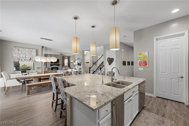 kitchen featuring dishwasher, hanging light fixtures, a center island with sink, a kitchen breakfast bar, and sink