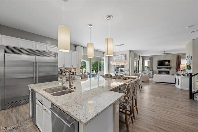 kitchen featuring decorative light fixtures, stainless steel appliances, a fireplace, and white cabinetry