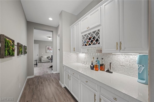 bar with white cabinets, light hardwood / wood-style flooring, and tasteful backsplash