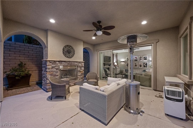 view of patio / terrace with ceiling fan and an outdoor living space with a fireplace