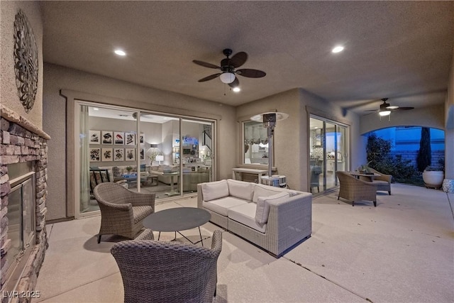 living room featuring a textured ceiling, ceiling fan, and an outdoor stone fireplace