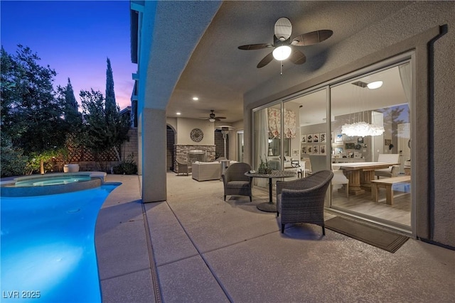 pool at dusk with ceiling fan, an in ground hot tub, and a patio area