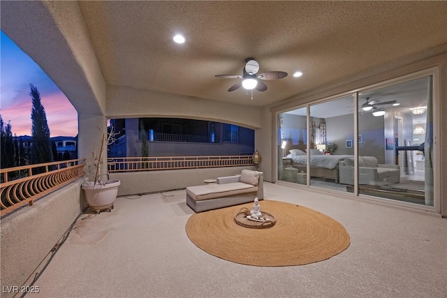 patio terrace at dusk featuring ceiling fan and a balcony