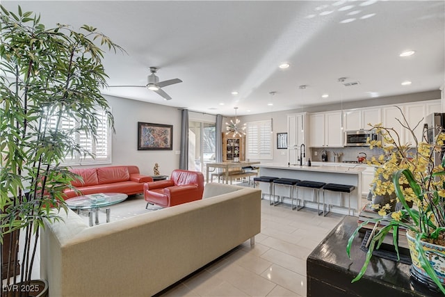 tiled living room with sink and ceiling fan with notable chandelier