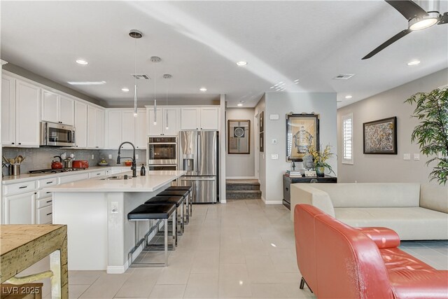 kitchen featuring stainless steel appliances, white cabinetry, hanging light fixtures, and sink