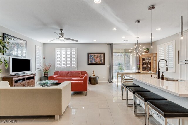 tiled living room featuring sink and ceiling fan with notable chandelier