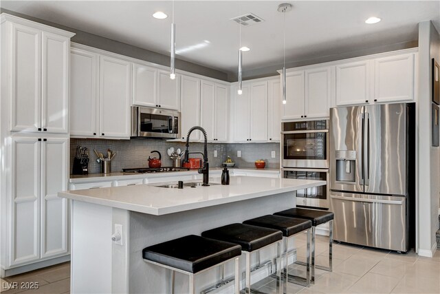 kitchen featuring appliances with stainless steel finishes, white cabinetry, a kitchen breakfast bar, and hanging light fixtures