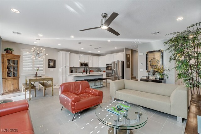 tiled living room featuring sink and ceiling fan with notable chandelier