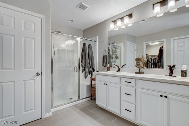 bathroom featuring vanity, tile patterned floors, a shower with shower door, and a textured ceiling