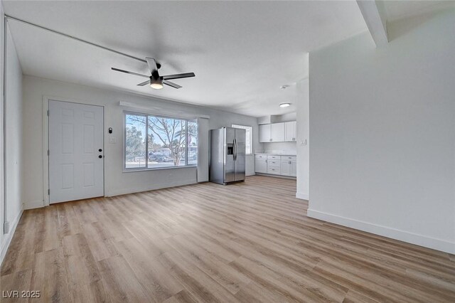 unfurnished living room featuring ceiling fan, beam ceiling, and light hardwood / wood-style flooring