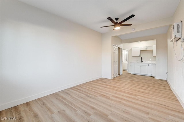 unfurnished living room with light wood-type flooring, a wall unit AC, ceiling fan, and sink