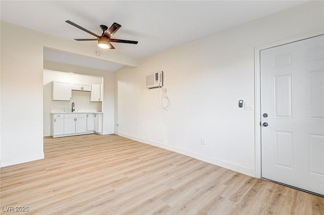 unfurnished living room with sink, a wall mounted air conditioner, light hardwood / wood-style flooring, and ceiling fan