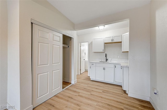 kitchen with white cabinets, light wood-type flooring, and sink