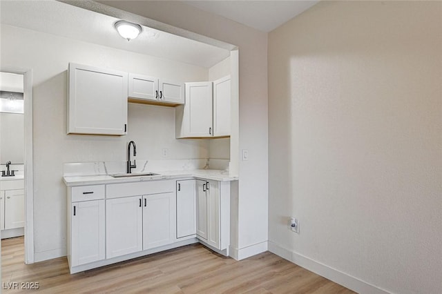 kitchen with sink, light hardwood / wood-style flooring, and white cabinetry