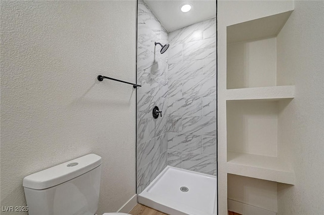 bathroom featuring toilet and tiled shower