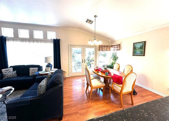 dining space with hardwood / wood-style flooring, crown molding, lofted ceiling, and french doors