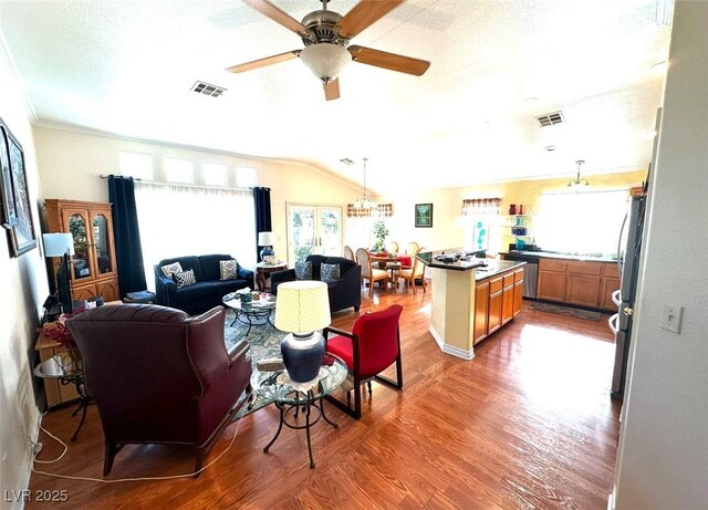 living room featuring ceiling fan, a textured ceiling, hardwood / wood-style flooring, and a healthy amount of sunlight