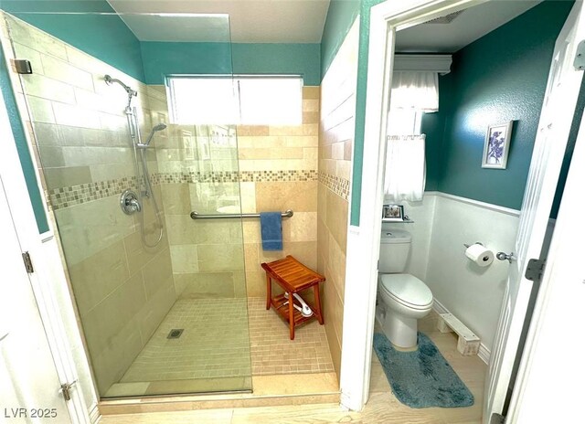 bathroom featuring toilet, tile patterned flooring, a tile shower, and plenty of natural light